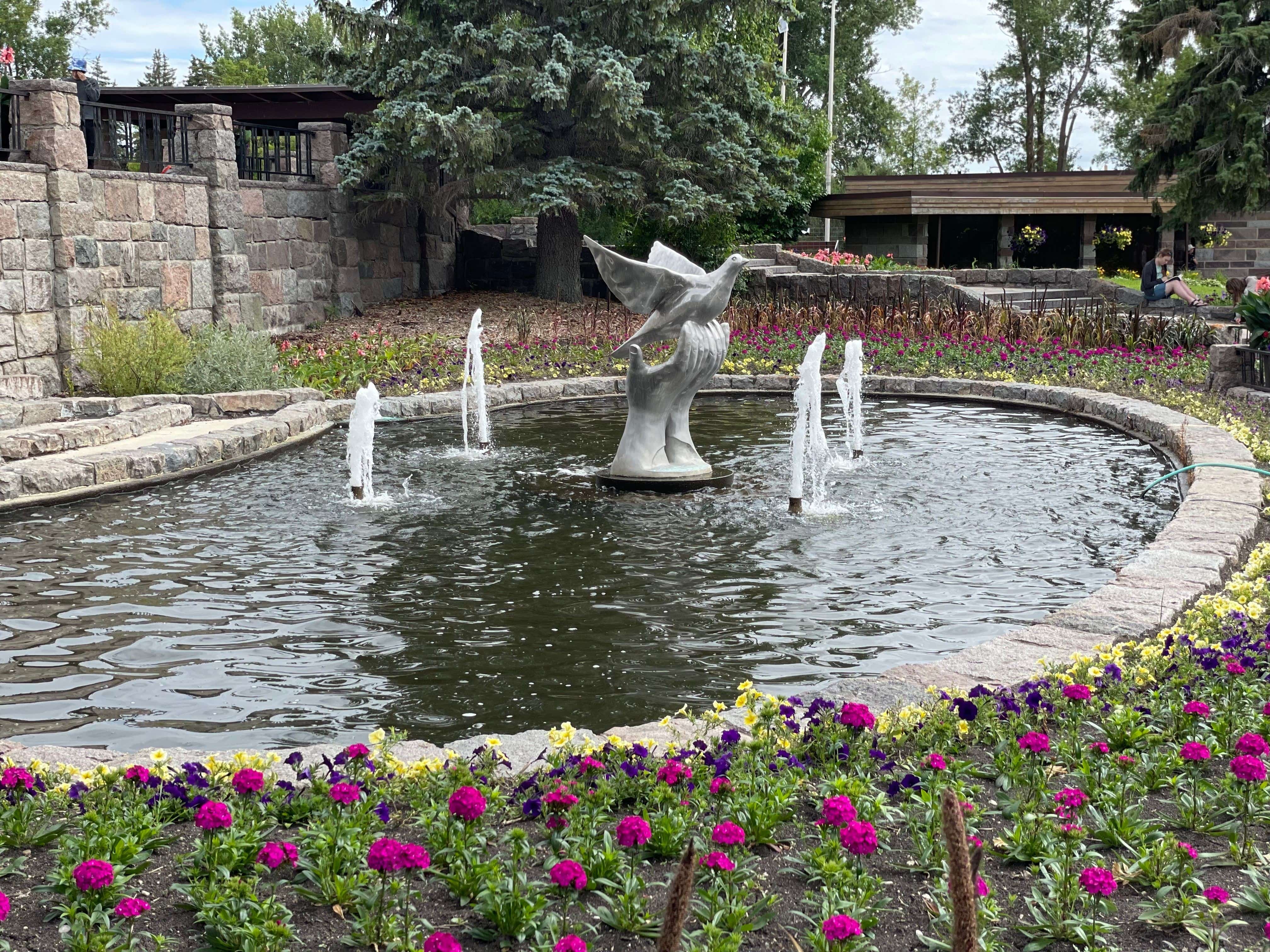 A sculpture of a hand holding a dove sits in a pond at the International Peace Garden. 